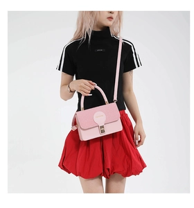 Détail du sac rose à fermoir montrant le rabat texturé et le logo rond FASHION embossé