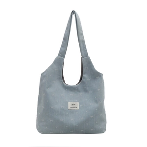 Light blue canvas hobo tote bag featuring white bow prints and a shoulder strap