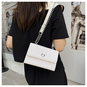 Detail of white crocodile embossed crossbody bag with silver twist lock and chain strap