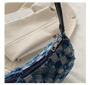 Dettaglio borsa a mezzaluna in denim blu con trama a scacchi sfrangiata e zip in metallo