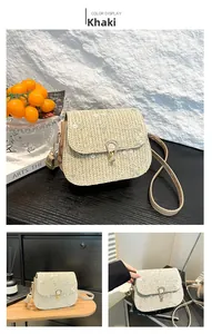 Close-up of khaki straw saddle bag featuring white floral embroidery and gold metal lock