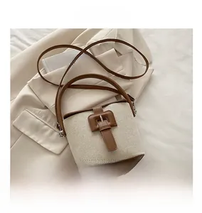 Détail d'un sac seau tissé avec bordure en cuir posé sur une veste beige chic