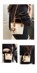 Detail of beige and brown bucket bag with butterfly embossing and plush monster charm