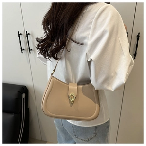 Minimalist beige leather shoulder bag with gold oval buckle shown on female model