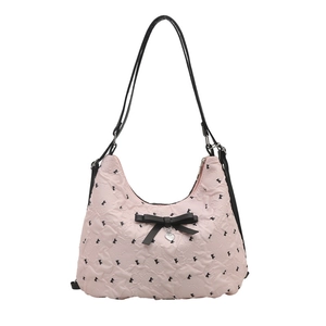 Sac bandoulière matelassé rose avec nœud noir et pendentif cœur sur fond blanc épuré
