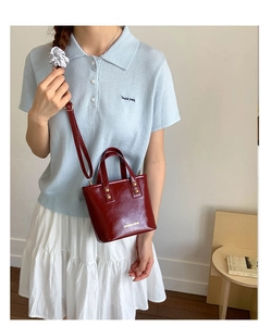 Detail of burgundy mini bucket bag with gold rivets and adjustable shoulder strap