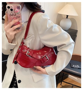 Red patent leather crescent bag with silver buckles and punk hardware on shoulder strap