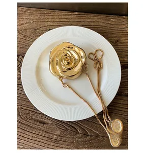 Detailed top view of a gold rose-shaped evening clutch with metal chain on a plate