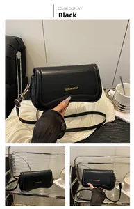 Detail view of black minimalist leather shoulder bag with gold hardware and logo print