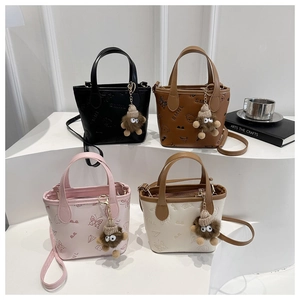 Detailed view of mini leather tote bags with embossed patterns and monster charms