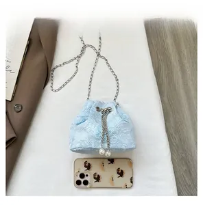 Detailed macro view of mini blue lace bucket bag with pearl drawstring and chain strap
