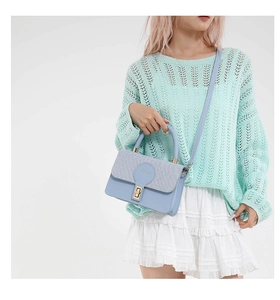 Détail du sac à main bleu clair avec rabat gris tissé et fermoir doré rotatif