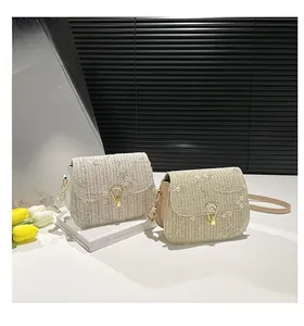 Close-up of exquisite floral embroidery and golden metal buckle on straw saddle bags