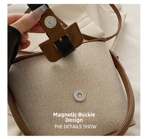 Détail du fermoir magnétique sur un sac seau rétro en tissu tissé beige et cuir brun