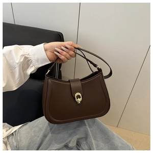 Dettaglio di una borsa sottobraccio minimalista in pelle testa di moro con fibbia dorata