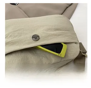 Detail of a beige nylon crossbody bag showing the functional side pocket with a metal button