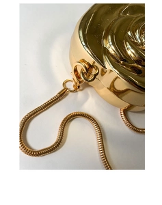 Close-up of golden rose-shaped evening bag showing embossed petals and snake chain