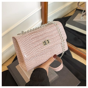 Détail de la texture croco rose et du fermoir rotatif argenté sur un sac à bandoulière