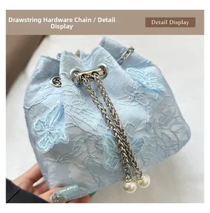 Detail of light blue lace bucket bag with butterfly embroidery and pearl chain
