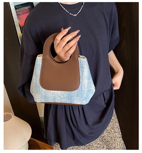 Detail of the blue denim bucket bag with brown leather handle and fine stitching