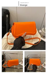 Detail of orange crossbody bag with gold FASHION & BAGS lettering and fine faux leather texture