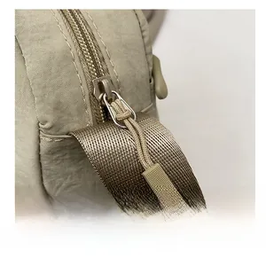 Close-up of smooth metal zipper and durable nylon fabric texture on khaki crossbody bag