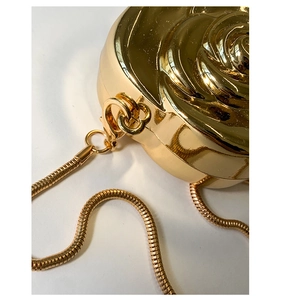 Macro shot of gold rose acrylic bag showing spiral petal relief and luxury snake chain