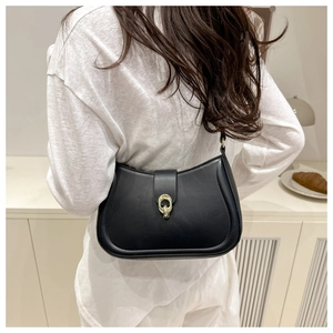 Dettaglio di borsa sottobraccio nera minimalista con fibbia dorata indossata da modella
