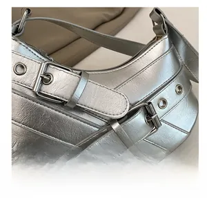Detail shot of silver crescent bag featuring metallic buckles and eyelet decorations