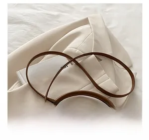 Vue détaillée de la bandoulière en cuir marron sur un sac seau en toile avec éclairage