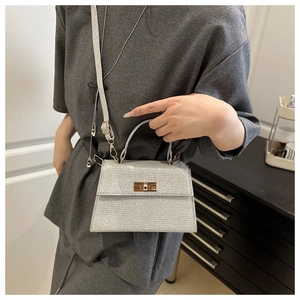 Detail of silver glitter crossbody bag showing trapezoidal shape and metal twist lock