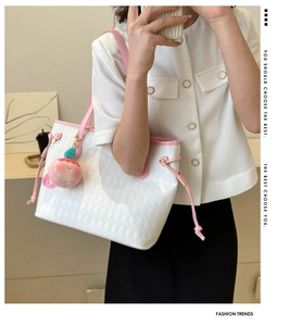 Detail of white quilted tote bag with pink leather handles and plush charm accessory