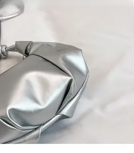 Detailed close-up of silver pleated faux leather crossbody bag with metallic finish