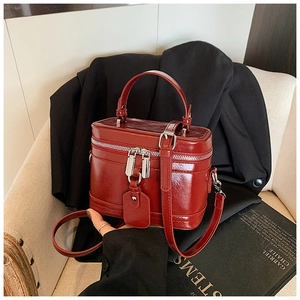 Detail of red wax leather box bag with silver zippers on a beige chair