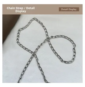 Close-up of the silver metal chain strap detail on a modern bucket handbag
