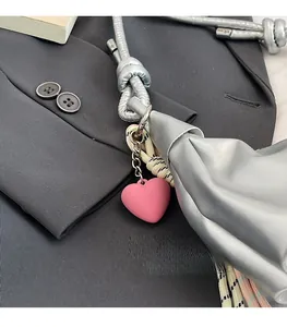 Detail of silver leather croissant bag with pink heart charm and knotted strap