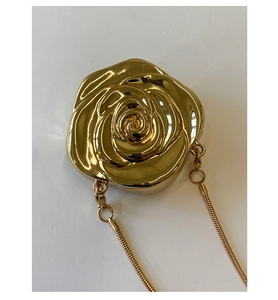 Close-up of golden rose-shaped evening bag with metallic petals and snake chain