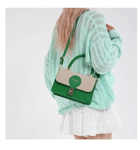 Détail du sac à main en cuir vert avec rabat tressé beige et fermoir doré rotatif