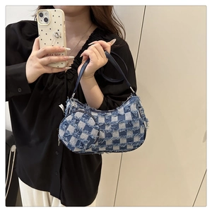 Dettaglio borsa a mezzaluna in denim a scacchi blu con bordi sfrangiati e mini pochette