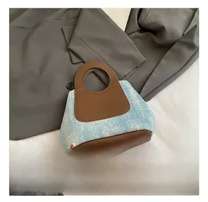 Detail of light blue sequined denim and brown leather stitching on a fashion bucket bag