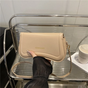 Chic beige leather shoulder bag with gold lettering shown in a modern urban setting