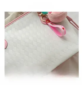 Detail of white woven tote bag with pink trim and a plush strawberry charm accessory
