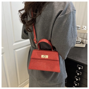 Detail of red glitter crossbody bag with golden turn-lock and adjustable shoulder strap