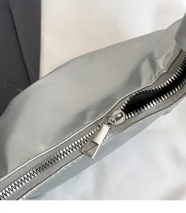 Detail of silver metallic dumpling bag featuring a premium sleek zipper and smooth PU leather