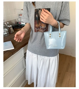 Detail of light blue mini tote bag with gold studs and embossed Fashion Bags text