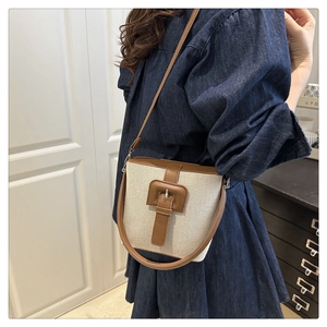 Détail du sac seau en toile avec bordure en cuir marron et boucle sur robe denim