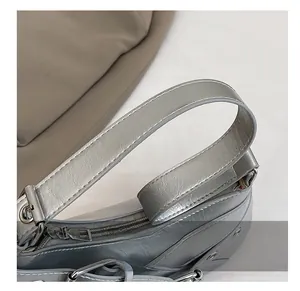 Detailed close-up of metallic silver shoulder strap with precise white stitching and hardware