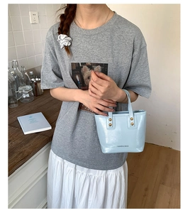 Detail of light blue bucket bag with gold rivets and 'FASHION & BAGS' text on smooth leather