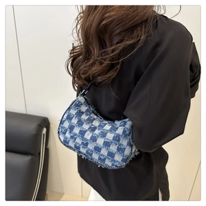 Dettaglio della borsa a mezzaluna a scacchi blu con eleganti bordi sfrangiati in denim