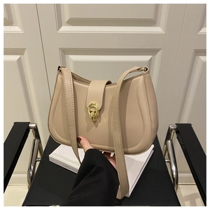 Dettaglio della borsa a spalla beige minimalista con fibbia dorata e cuciture di precisione
